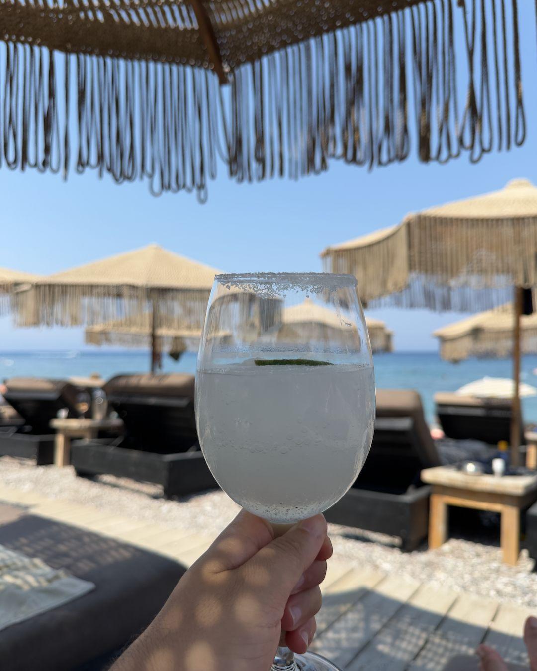 Rodos VLOG ve Gezi Rehberi Rodos'taki Ronda Beach Club'ın şık hasır şemsiyeleri ve konforlu şezlongları