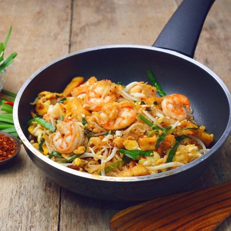 Pad Thai Tarifi (Tavuklu & Karidesli & Sebzeli): Lezzetli sosuyla harmanlanmış tavuk, karides ve taze sebzelerle zenginleşen pirinç noodle'ları, üzeri kıtır yer fıstığı, taze kişniş ve bir dilim misket limonu ile süslenmiş iştah açıcı sunum.