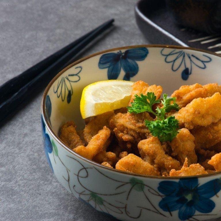 Japon usulü Tori Karaage tarifi: Soya sosu ile marine edilmiş ve nişasta ile kaplanarak çift kızartma tekniğiyle pişirilmiş çıtır tavuk parçaları, yanında limon dilimiyle servis ediliyor.