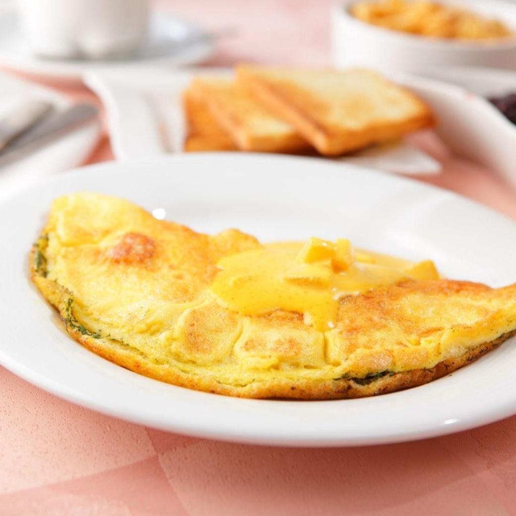 Servis tabağında ikiye katlanmış, içinden yeşil zeytin ezmesi görünen ve üzeri maydanozla süslenmiş lezzetli omlet.