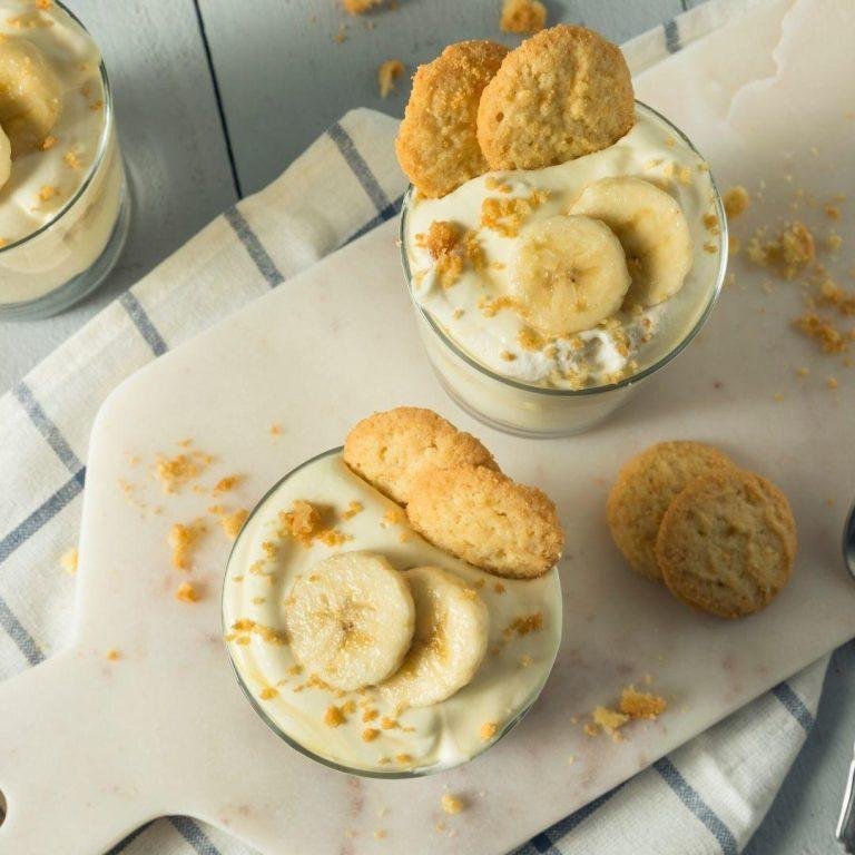 Cam bir kasede servis edilen, üzeri muzla süslenmiş, pürüzsüz ve tam kıvamında sade sütlü muhallebi.