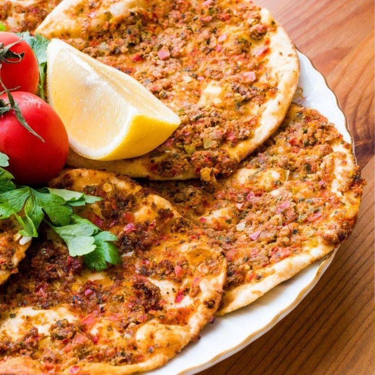 Tavada pişmiş, altı çıtır üstü bol harçlı ev yapımı lahmacun görüntüsü; geleneksel Türk mutfağının vazgeçilmezi olan lahmacun tabakta sunulmuş, yanında ince doğranmış maydanoz ve limon dilimleriyle servis edilmiş görsel.