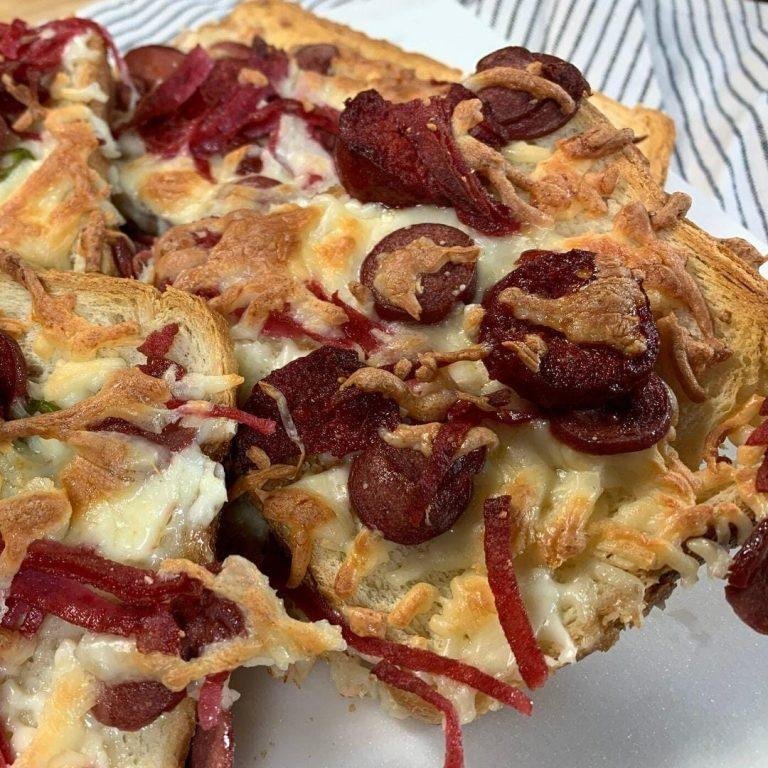 Fırından yeni çıkmış, erimiş kaşar peyniriyle uzayan, yeşil biber ve sucuk parçalarıyla süslenmiş, çıtır bayat ekmek dilimleri üzerinde sunulmuş enfes bayat ekmekten pizza görünümü