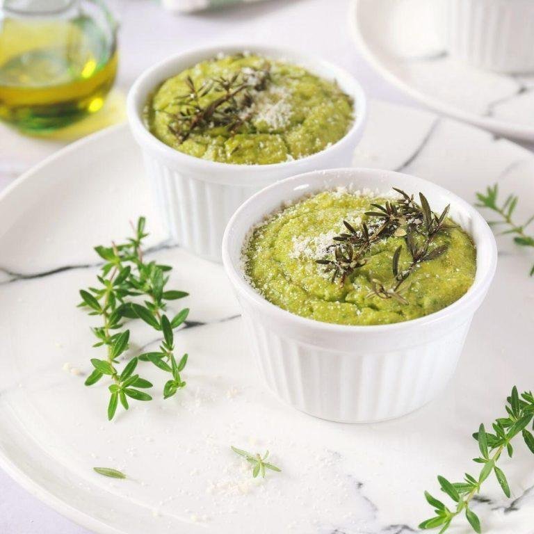 Altın rengi ile fırında kabarmış, içi beyaz peynirle bezeli nefis bir brokoli sufle; yanlarında buharda haşlanmış brokoli demetleriyle sunumda göz alan bir tabak görüntüsü.