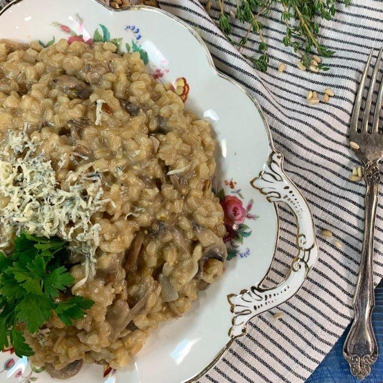 Dumanı üstünde servis edilen, parmesanla kaplanmış, taze otlarla süslenmiş kremalı buğday risotto tabağı – tam kıvamında pişmiş sağlıklı bir alternatif