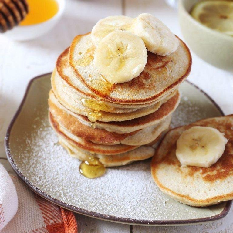 Altın rengiyle göz alan, meyve ve soslarla süslenmiş, kabarık ve iştah açıcı glutensiz pankekler servis tabağında hazır bekliyor