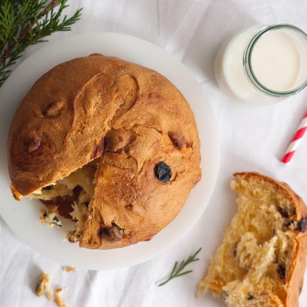 Yumuşacık dokusuyla fırından yeni çıkmış, içi kuru meyve dolu, üzeri çatlamış ve altın kahverengi görünümüyle bir dilim panettone kek – yılbaşı sofralarına özel nostaljik lezzet!