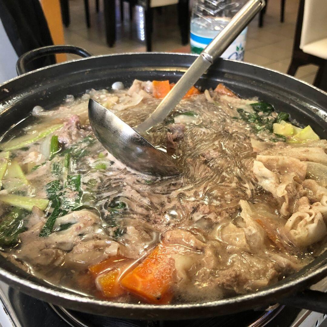 Seorabeol'da masa ocağında pişen bulgogi-jungol: et suyu, sebzeler ve patates noodle