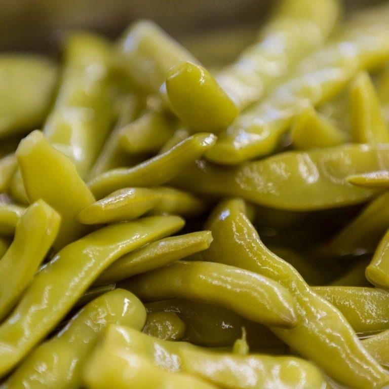 Karadeniz usulü kıtır fasulye turşusu kavanozda sunulmuş, yanında sarımsak ve sirke şişesiyle fermente olmuş leziz bir ev yapımı fasulye turşusu