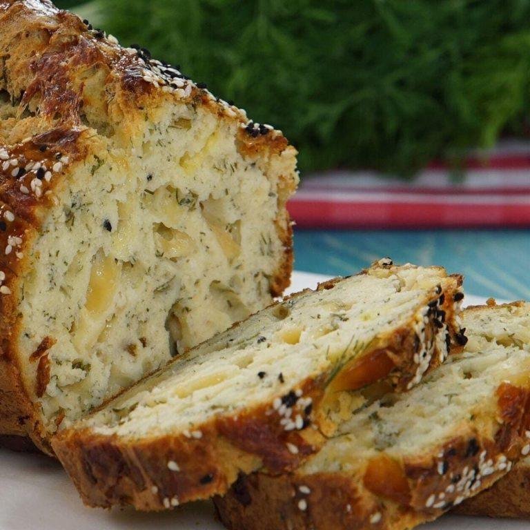 Fırından yeni çıkmış, üstü çörek otu ve susamla süslenmiş, içi dereotu ve hellim peyniriyle bezeli nefis bir hellimli kek dilimi görüntüsü