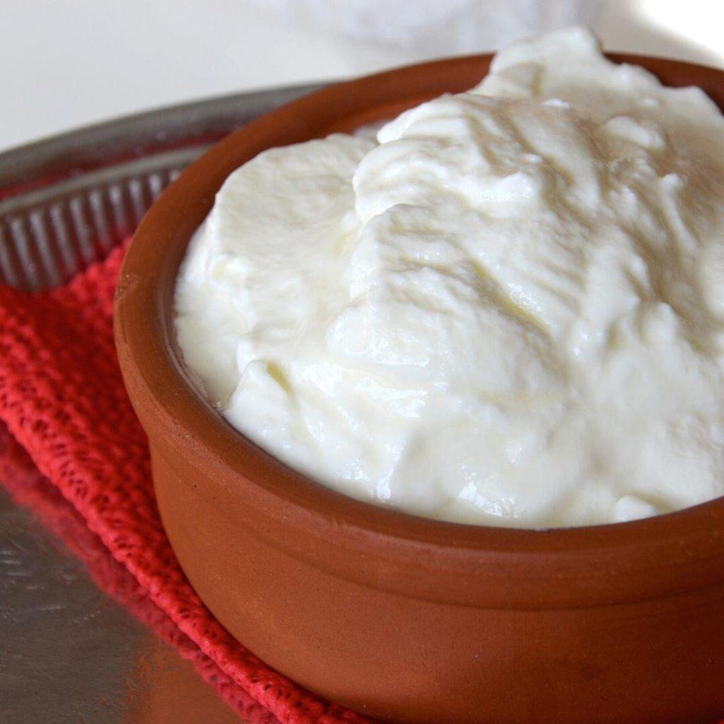 Evde taş gibi kıvamında mayalanmış, pürüzsüz yüzeyli ve cam kasede sunulan yoğurt görseli – süzme yoğurt, bebek yoğurdu, probiyotik yoğurt, vegan yoğurt dahil tüm yoğurt tariflerine ilham verir