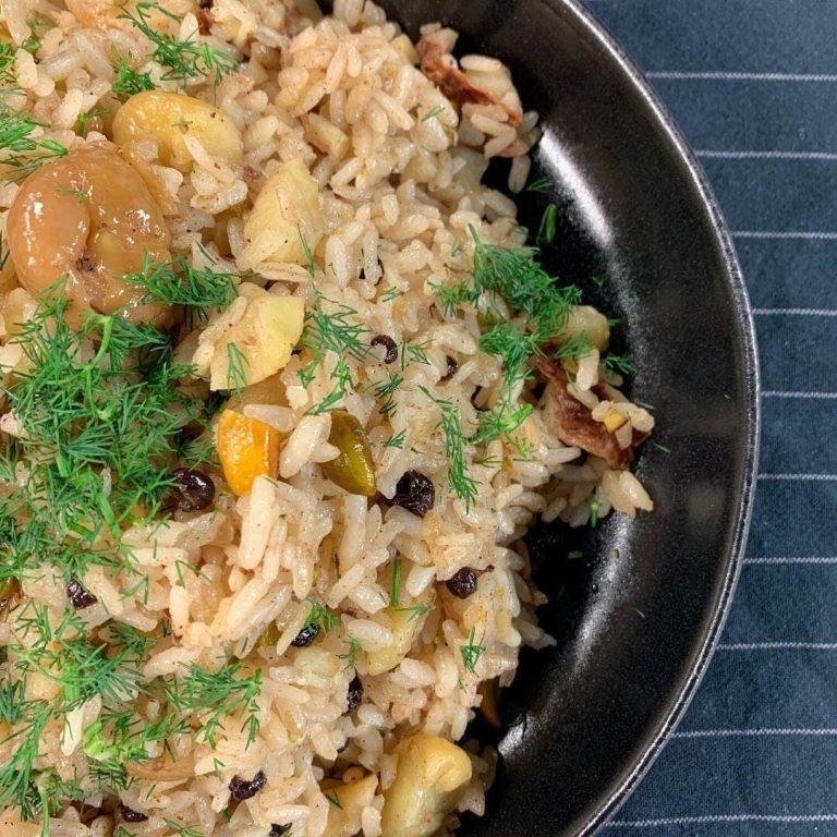 Tane tane dökülen kestaneli pilav tarifi: Bol kestane, kuş üzümü ile hazırlanmış, dumanı tüten geleneksel yılbaşı iç pilavı servis tabağında sunuluyor.