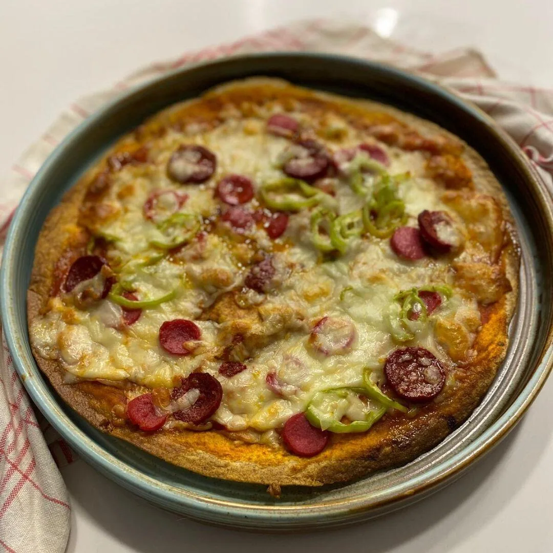 Lavaş pizza dilimlenmiş; çıtır lavaş taban üzerinde sos, eriyik kaşar ve sucuk