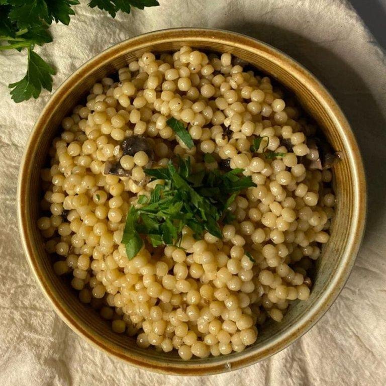 Kremalı Mantarlı Kuskus Pilavı Tarifi: İrmikten yapılan kuskusla buluşan zengin mantar ve krema sosunun sıcak buharıyla süzülen pratik ve doyurucu bir fırın yemeği görüntüsü