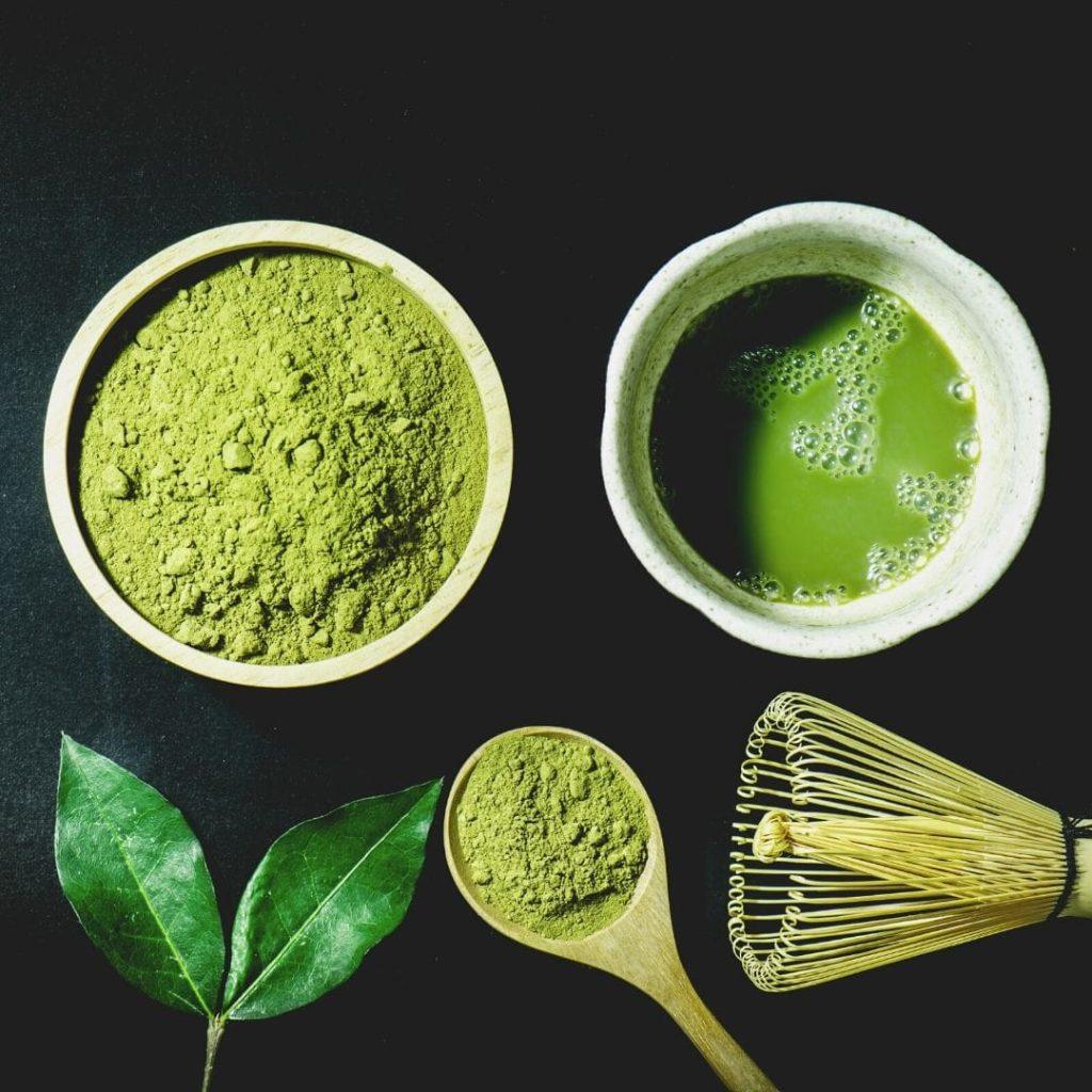 Matcha çayı kâsede; canlı yeşil renkli, üzeri köpüklü, yanında bambu çırpıcı
