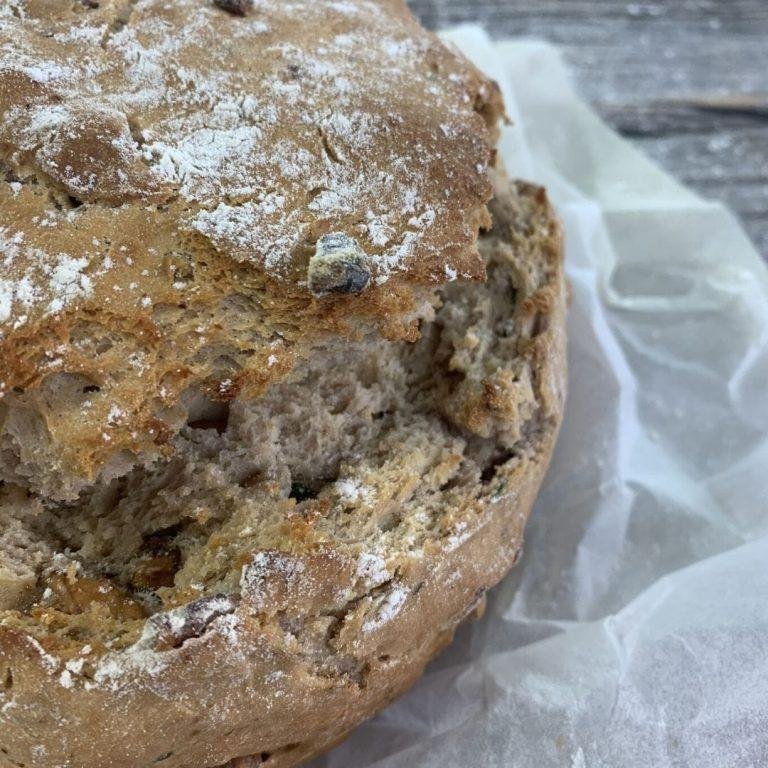 Ceviz ve taze kekik ile süslenmiş, altın renginde kızarmış, kabuğu çıtır çıtır bir mayasız yoğurtlu ekmek görseli. Yanında maden suyu ve yoğurt ile doğal sunum tamamlanmış.