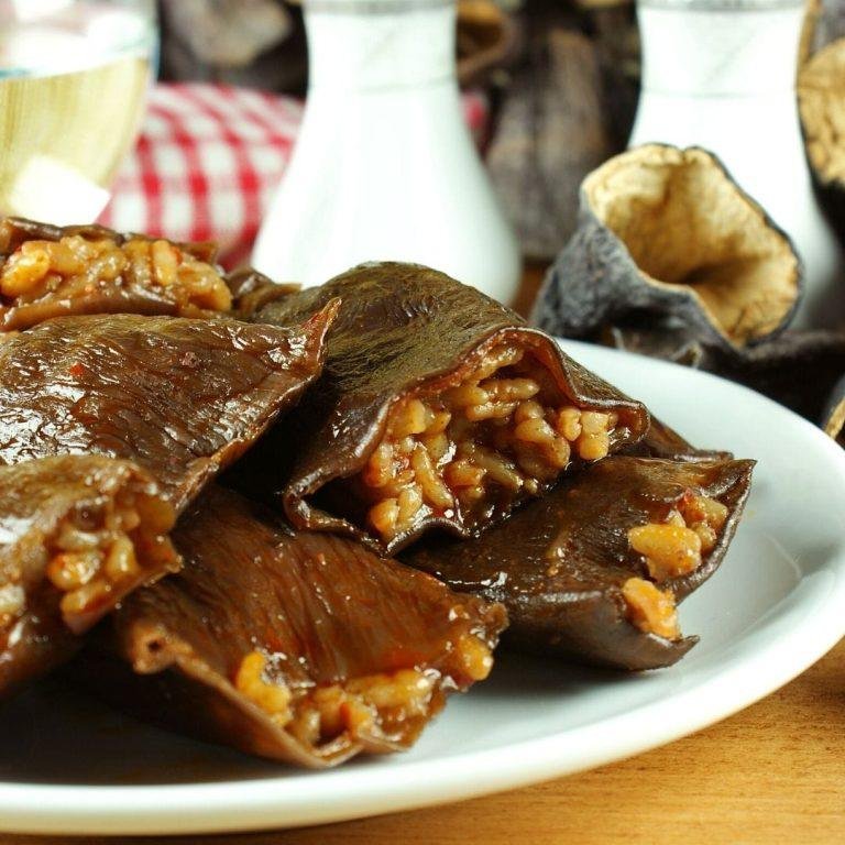 Kuru Patlıcan Dolması Tarifi görseli: Tencere içinde dizili kıymalı içle doldurulmuş kuru patlıcan dolmaları, üzerine gezdirilmiş zeytinyağı ve taze yeşillikler ile otantik bir sunum. kuru patlıcan dolması, nasıl yapılır, kıymalı, zeytinyağlı, kalorisi, antep usulü gibi lezzet severlerin aradığı tüm detayları yansıtır.