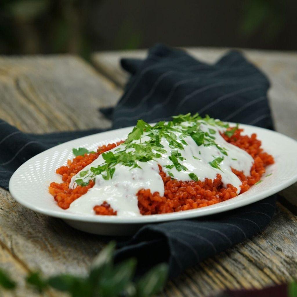 Pezzik; pancar suyuyla pişmiş kırmızı bulgur pilavı, üzeri sarımsaklı yoğurtlu