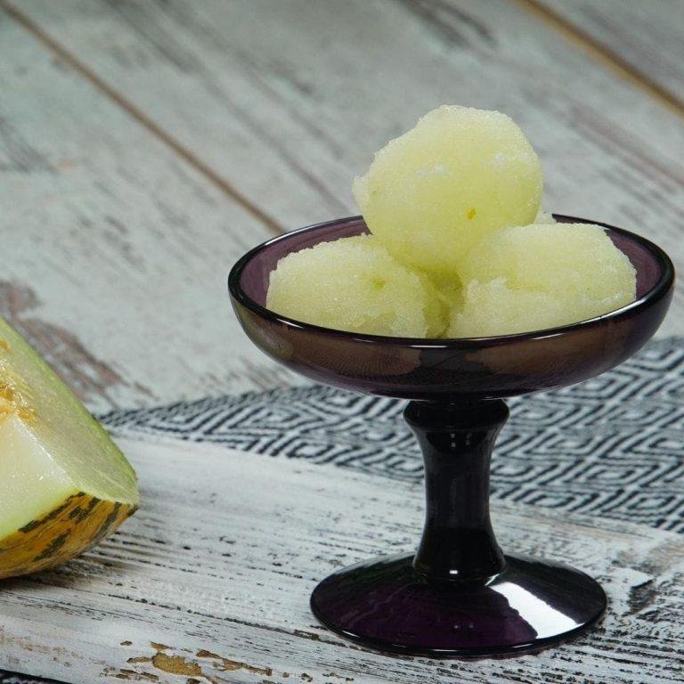 Canlı turuncu rengiyle iştah açan, buz gibi ferahlatıcı ve pürüzsüz kıvamıyla ağızda eriyen, taze fesleğen yaprağıyla süslenmiş, tamamen doğal malzemelerle hazırlanan lezzetli bir kavunlu sorbe.