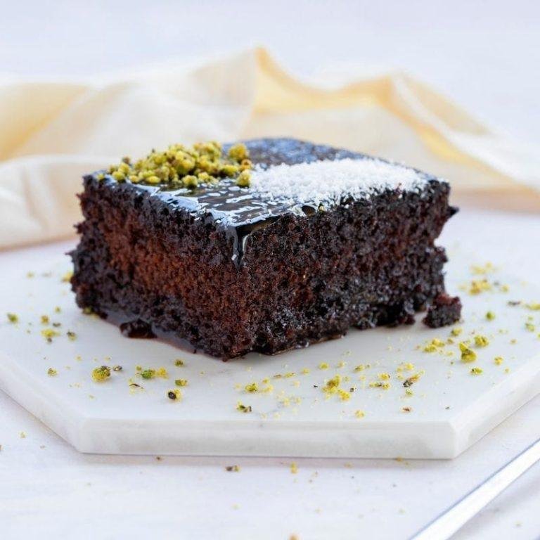 Yoğun kakaolu, bol soslu ve browni tadında bir dilim ıslak kekin çayla buluştuğu anı gösteren, üzeri parlayan nefis ıslak kek fotoğrafı
