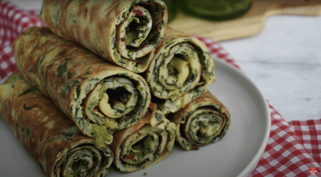 Ege otlarıyla, özellikle taze fesleğenle zenginleşen, altın sarısı kızarmış, pofuduk ve kıvamlı kaygana; doğal malzemelerin canlı yeşil tonlarıyla iştah açıcı bir görsel şölen sunuyor.