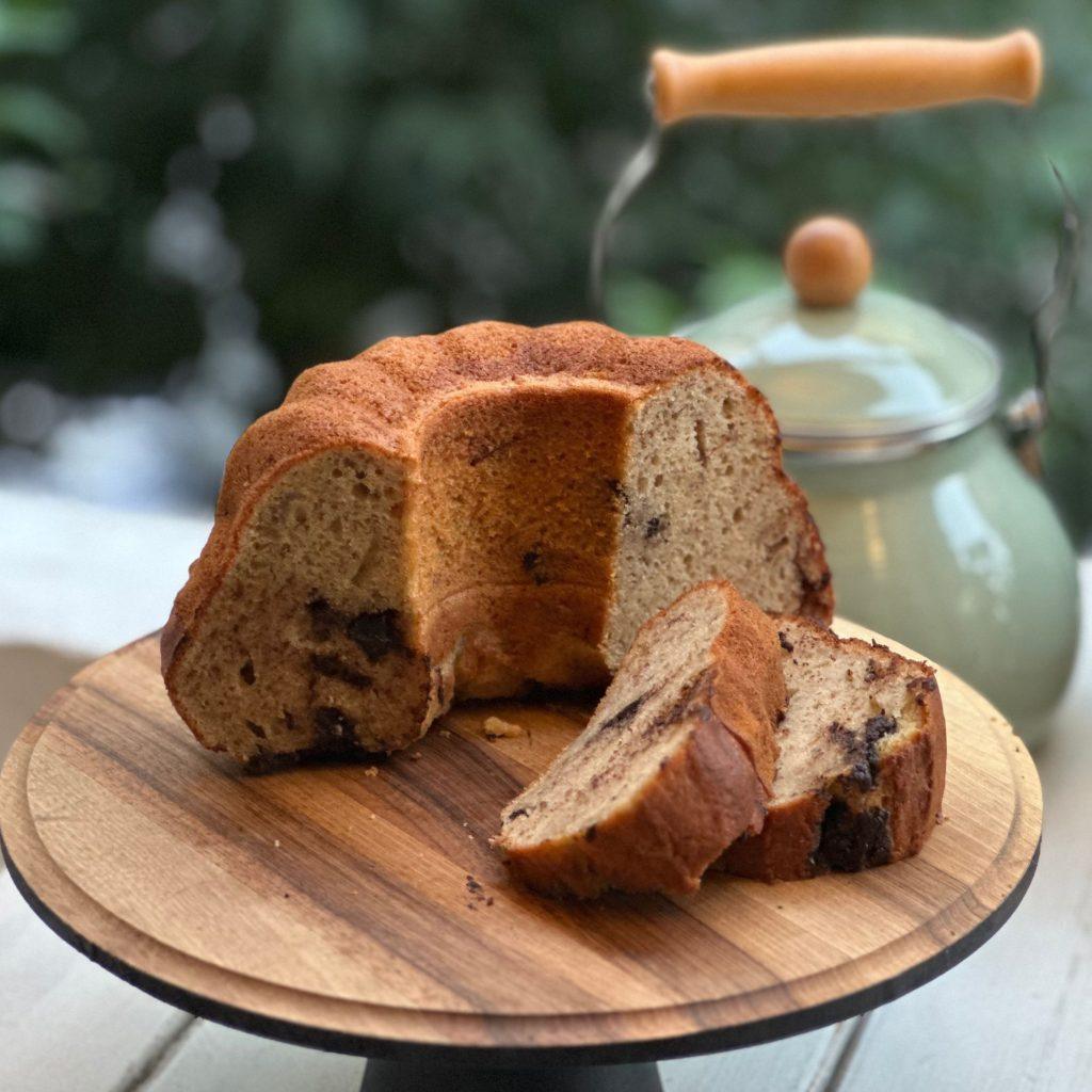 Fırından yeni çıkmış, üzerinde erimiş bitter çikolata parçalarıyla süslenmiş yumuşacık çikolatalı muzlu kek dilimleri