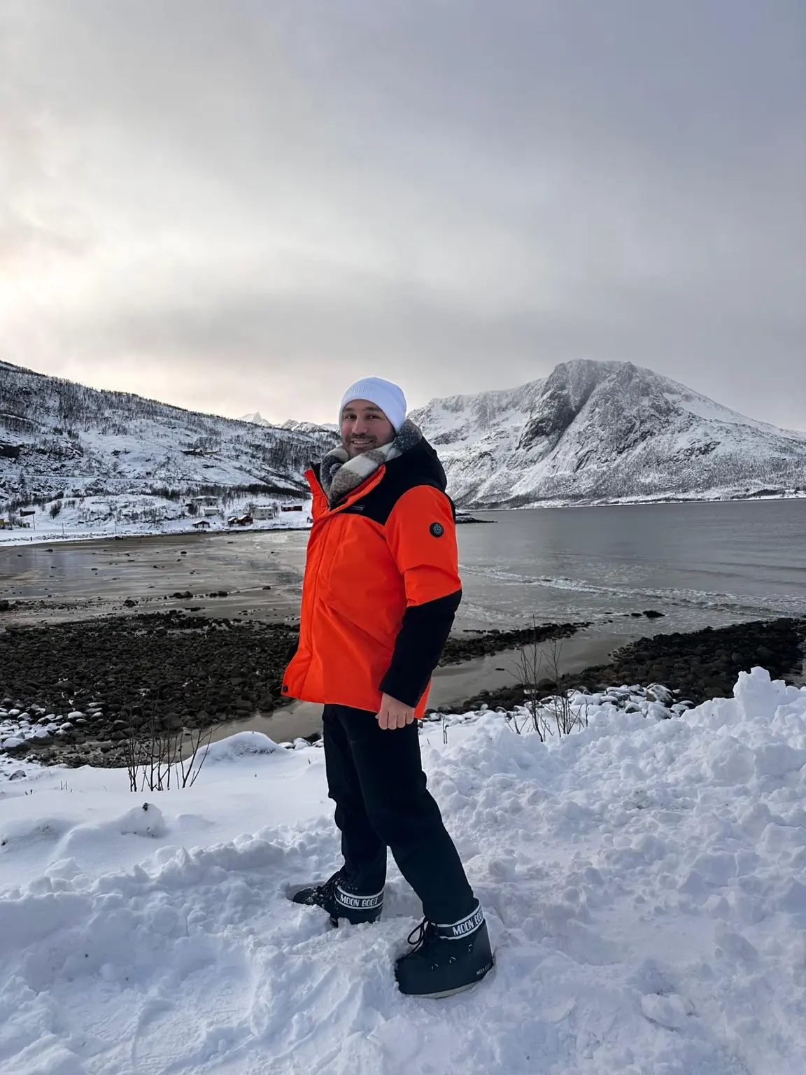 Tromso VLOG ve Gezi Rehberi : Kuzey Işıkları'nın Başkenti Tromsø'de fiyort kenarında kışlık giysilerle duran bir gezgin