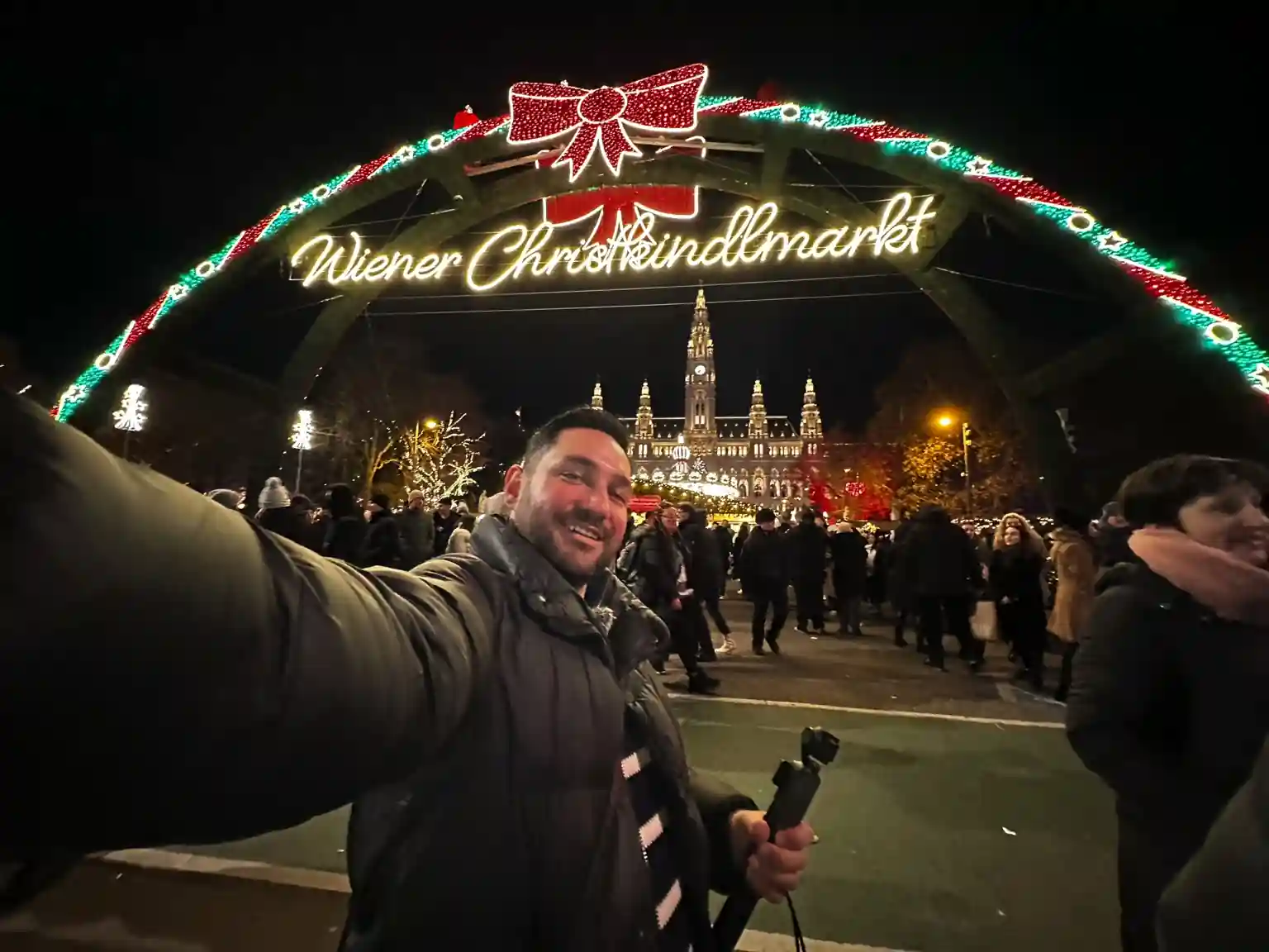 Viyana'da bir Noel pazarının genel görünümü, ışıklı tezgahlar ve kalabalık insan grupları.