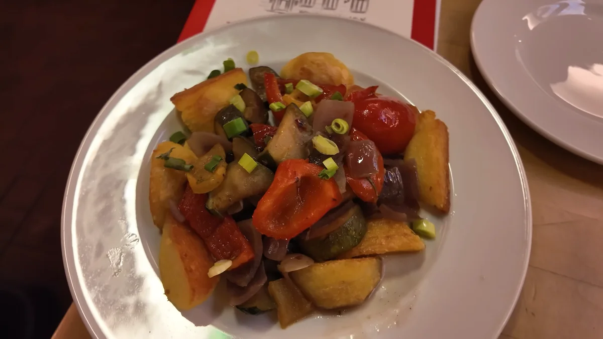 Fried potato dumplings served with red pepper, onion and spring onion at a historic restaurant in Cologne