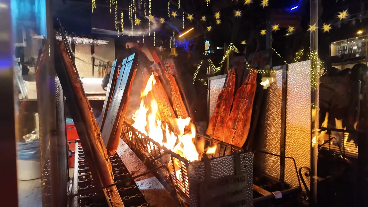 Salmon fillets cooking over an open fire at the Lachs König stall, Neumarkt Christmas market, Cologne