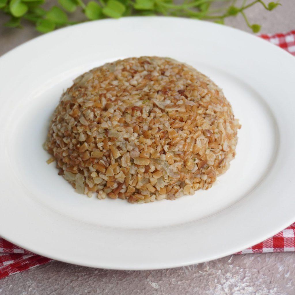 Siyez Bulguru Pilavı: Tane tane ayrılmış, buharı tüten altın sarısı siyez bulgurlarının oluşturduğu pilav, üzerinde taze yeşil fesleğen yapraklarıyla süslenmiş, hafif parlak ve kıvamlı doğal dokusuyla iştah kabartan bir sunum.