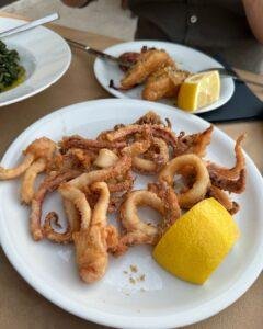 Symi Adası'nda bir restoranda servis edilmiş, yanında limon dilimi bulunan çıtır kalamar tava tabağı.