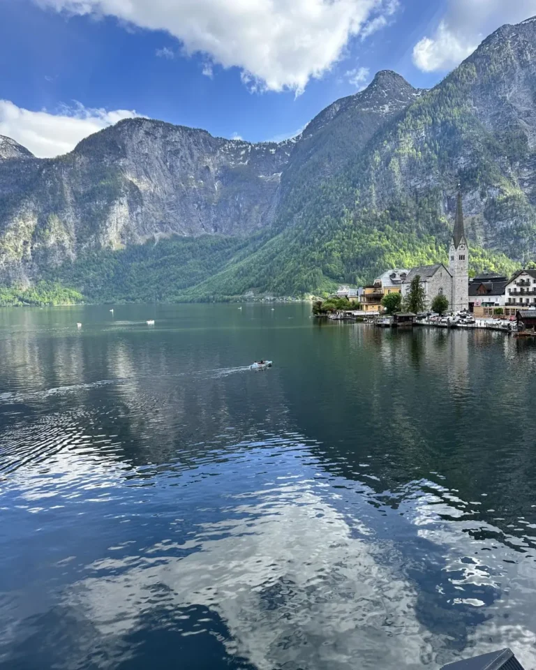 Hallstättersee gölünün ayna gibi yansıması ve sağ kıyıda Hallstatt Evangelik Pfarrkirche kilisesinin uzun çan kulesi