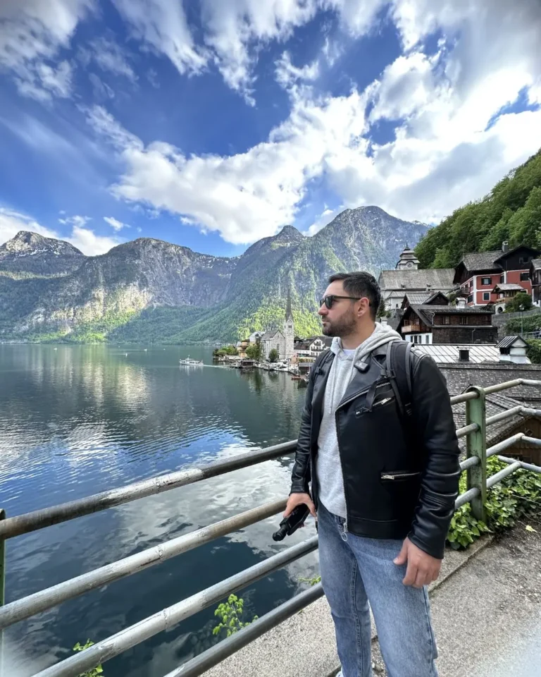 Hallstatt klasik fotoğraf noktasında göl kenarındaki demir korkulukta Gezginbirchef, arkada Evangelik Kilise ve yolcu teknesi
