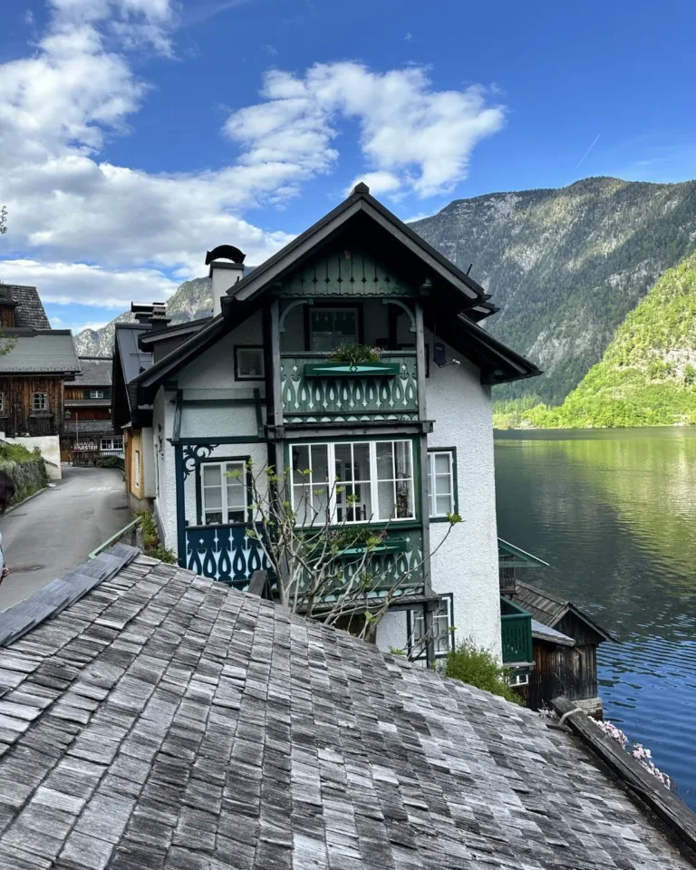 Hallstatt'ın yeşil ahşap işlemeli geleneksel Avusturya evi ve gölün üzerindeki tipik ahşap çatı manzarası