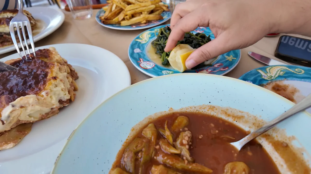 Tinos’ta Pi Fi’de ev yemekleri: pastitsio, bamya yemeği, horta ve patates kızartması aynı masada