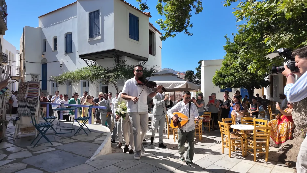 Tinos'ta Pyrgos Köyü: çınarlı meydanda düğün alayı, keman ve buzuki çalan müzisyenler, alkışlayan kalabalık