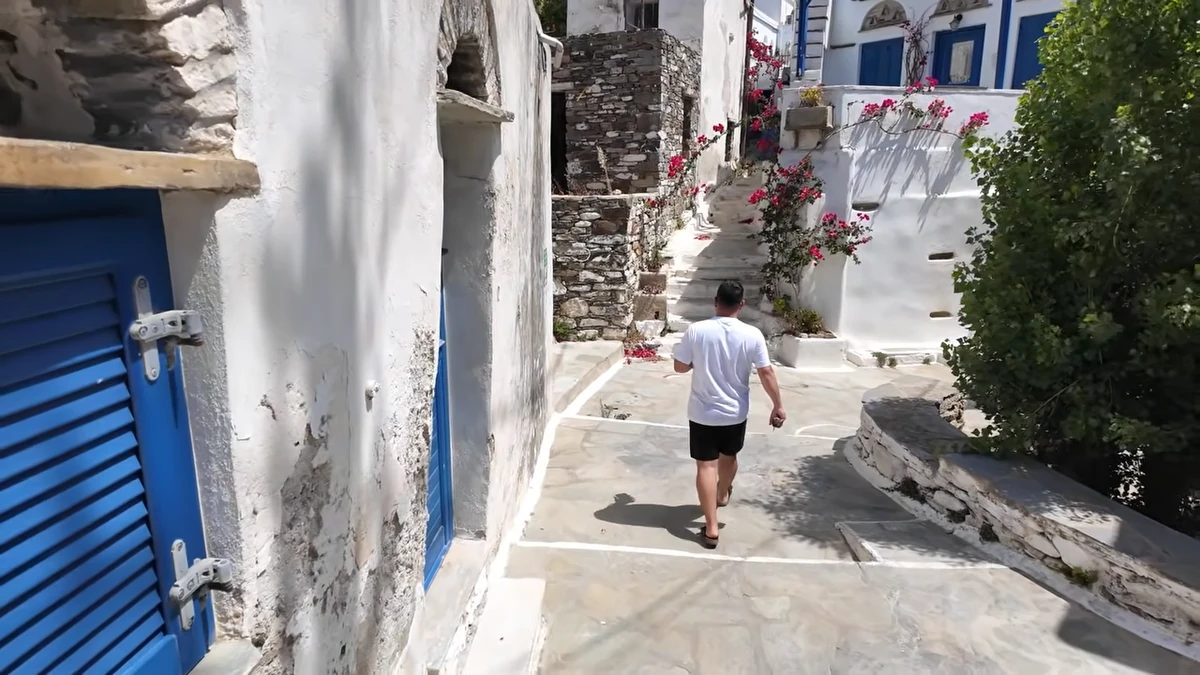 Tinos'ta Tripotamos Köyü: begonvillerle kaplı dar sokak, mavi kepenkler ve yukarı çıkan taş merdivenler