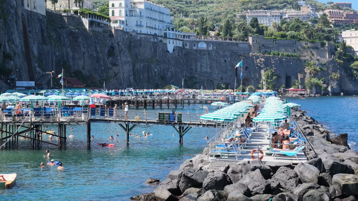 Sorrento sahilinde kayalıkların üstüne kurulmuş şemsiyeli ahşap platformlar
