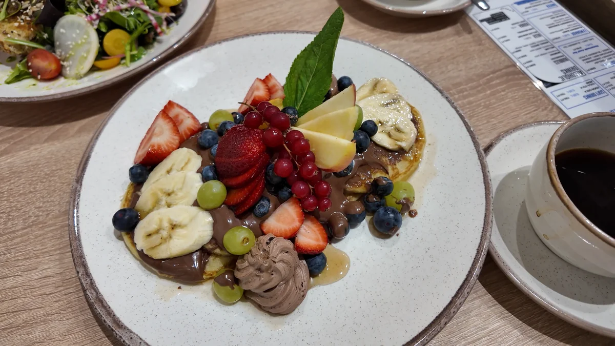 Budapeşte Blueberry Brunch’ta çilek, yaban mersini ve muzlu pankek tabağı, yanında filtre kahve