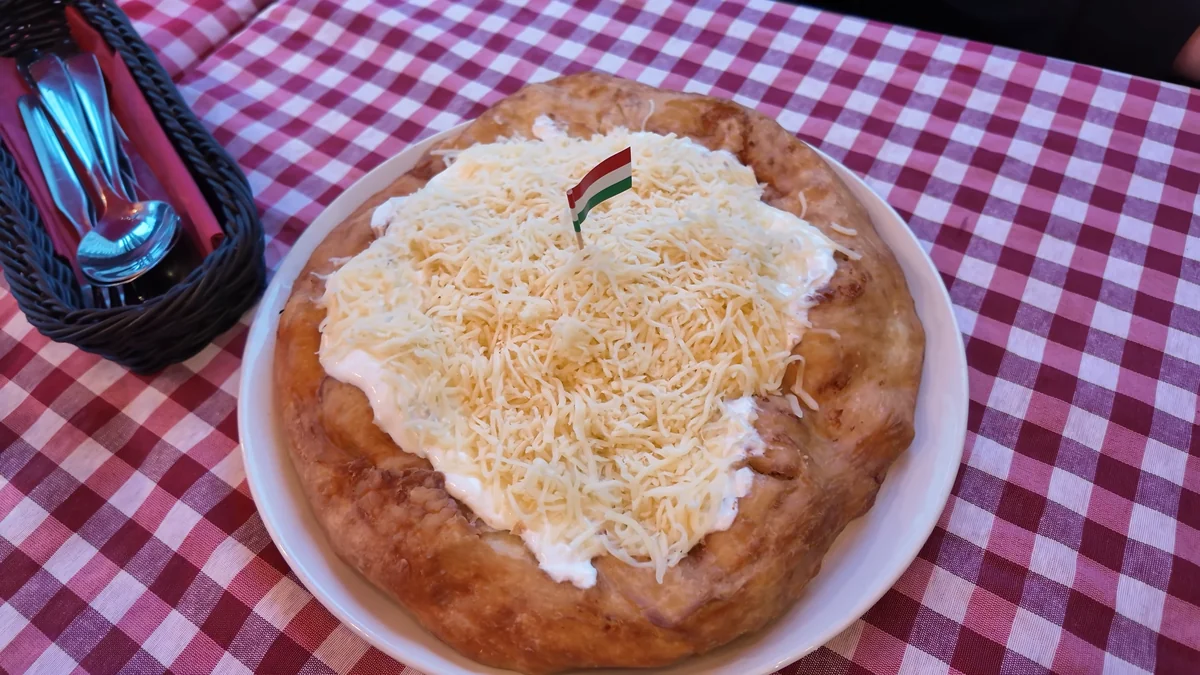 Budapeşte’de ekşi krema ve rendelenmiş peynirle servis edilen langoş, kırmızı beyaz kareli masa örtüsünde