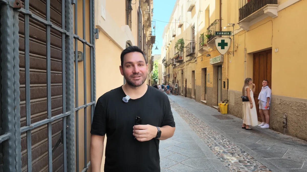 Cagliari Castello mahallesinin dar sokağı, sarı cepheli evler ve eczane tabelası