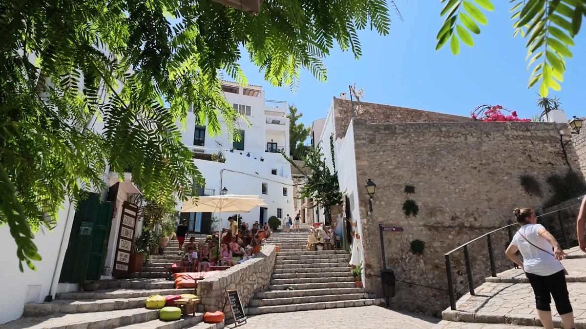 İbiza Dalt Vila’da S’Escalinata: taş merdivenlere serilmiş renkli minderler ve oturan misafirler