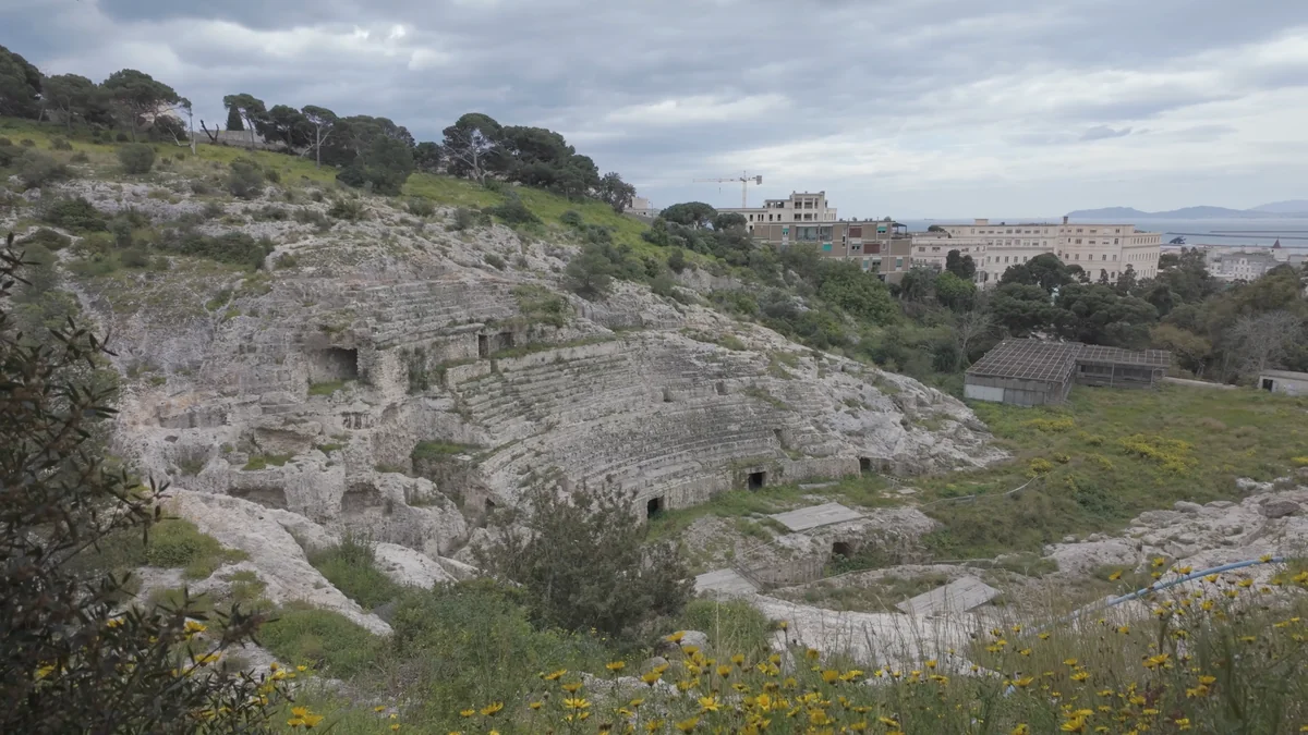 Cagliari Roma Amfitiyatrosu'nun kayaya oyulmuş basamakları, arkada şehir ve deniz