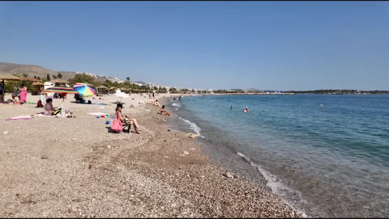 Pebbly beach with umbrellas and calm sea on the Glyfada coast