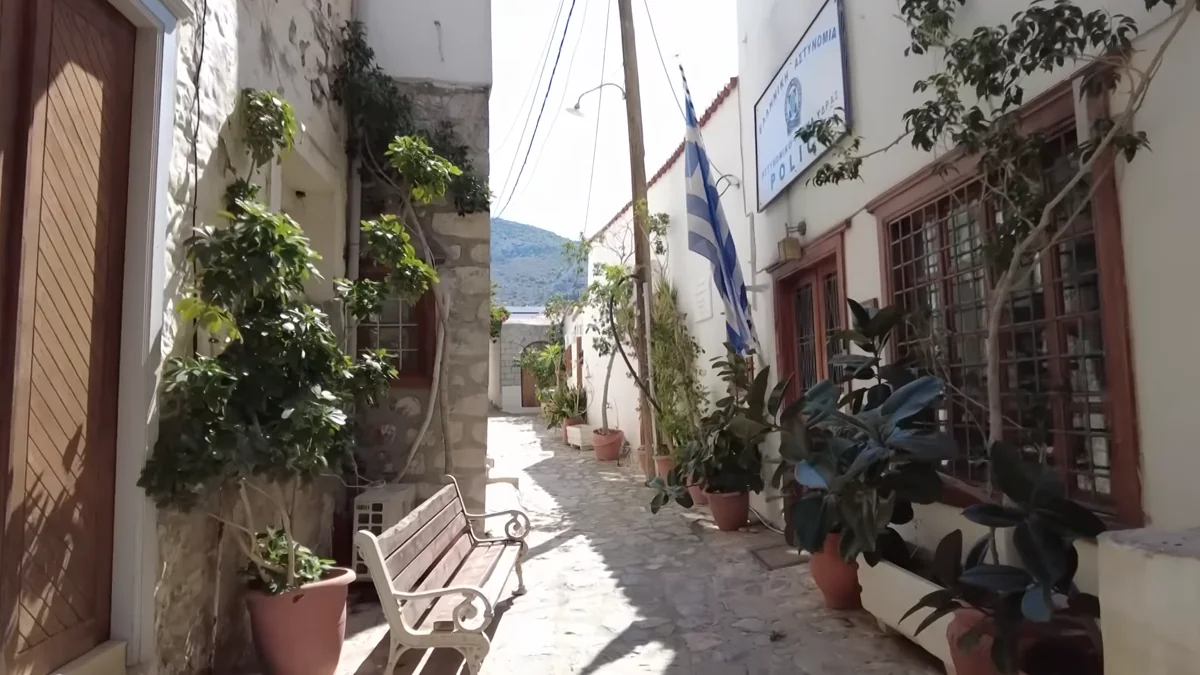 Hydra'da beyaz badanalı evler ve Yunan bayraklı taş sokak