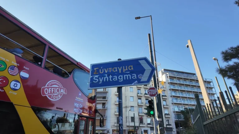 Kırmızı hop-on hop-off tur otobüsü ve Syntagma yön tabelası