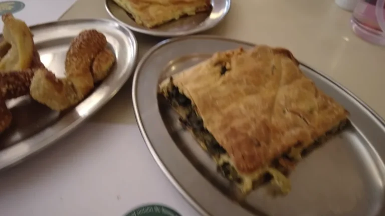 Spinach and cheese pie slices on metal plates at Veneti, Athens