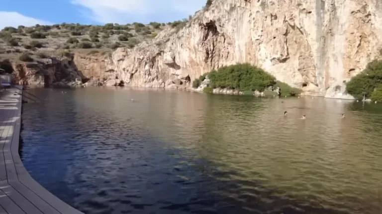 Lake Vouliagmeni beneath limestone cliffs with a wooden deck