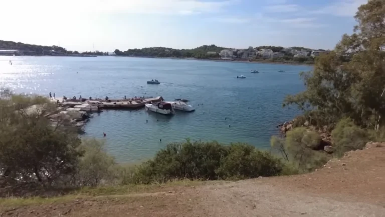 A jetty, boats and rocky shore in Vouliagmeni bay